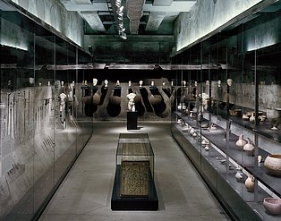 Dauerausstellung 6m, Geschichte  Blick auf verschiedene archäologische Objekte wie ein Sarkophag, Vasen, Werkzeuge und Büsten in Ausstellungsvitrinen auf der 12-Meter-Ebene der Dauerausstellung des Ruhr Museums